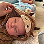 Logan joined the competition — help win amazing prizes! baby, sleeping, onesie, animal_costume, hood, hand, child, pajamas, couch, living_room, blanket, soft_texture, face, peaceful, indoor, cozy, person, home, pillow, cute