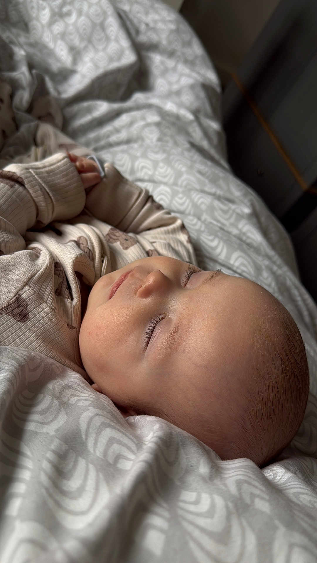 Logan is registered to the contest to win money with this photo: baby, sleeping, blanket, bed, onesie, infant, closeup, peaceful, soft_lighting, indoors, face, child, newborn, cozy, patterned, rest, cute, hands, skin, portrait