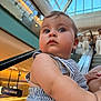 baby, child, striped_clothing, mall, indoor, escalator, curious, wide_eyes, portrait, person, blue_eyes, skin, short_hair, holding, shopping_center, modern, daylight, close_up, human, casual