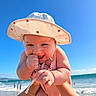baby, child, sun_hat, strawberry_print, beach, ocean, sky, smile, hand, arm, water, waves, summer, sunny, outdoor, cute, playful, person, happy, infant