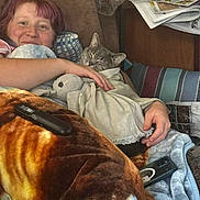 Jackson joined the competition — help win amazing prizes! person, cat, blanket, couch, pillow, smile, indoor, relaxing, cozy, sleepy_cat, newspaper, wood_paneling, remote_control, hand, plush_toy, phone, comfort, resting, casual, home