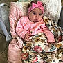 baby, baby_seat, big_eyes, blanket, bouncer, bow, cardigan, cheeks, cozy, fingertips, floral_blanket, gaze, hand, headband, indoor, infant, pink_clothing, plush, portrait, tiled_floor
