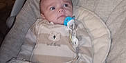 Paul participe au concours pour gagner de l'argent avec cette photo : baby, infant, pacifier, bouncer, baby_bed, blanket, swaddle, onesie, striped_clothing, toy, plush, indoor, dim_lighting, portrait, face, head, hand, cozy, nursery, curious_expression