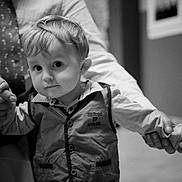 Lucas participe au concours pour gagner de l'argent avec cette photo : toddler, child, person, hand, adult, holding_hands, clothing, vest, shirt, face, hair, indoors, floor, window, tie, black_and_white, portrait, expression, curious, closeup