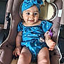 baby, child, blue_outfit, headband, stroller, cushion, smile, happy, infant, cute, plush_toys, indoor, person, skin, hand, legs, pacifier, clothing, seat, toy
