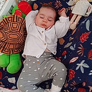 Salomé participe au concours pour gagner de l'argent avec cette photo : baby, sleeping, infant, blanket, toy, doll, plush, bed, pajamas, white_sweater, patterned_pants, sock, cozy, child, resting, cute, nursery, peaceful, soft_toys, indoor