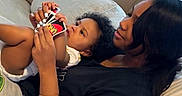 Kaliyanei joined the competition — help win amazing prizes! adult, bedroom, black_shirt, child, couch, cozy, cuddling, curly_hair, family, home, indoors, lying_down, mother, parent, pillows, playing_cards, portrait, sitting, smiling, toddler