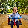 child, toddler, swing, playground, park, trees, autumn, outdoor, blue_sweater, navy_leggings, brown_shoes, happy, smiling, daylight, chains, play_equipment, nature, leaves, cute, person