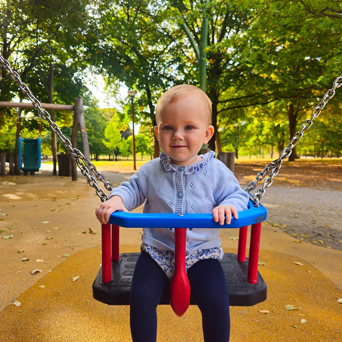 Servane a rejoint le concours — aidez-le/la à gagner de superbes lots ! autumn, blue_sweater, brown_shoes, chains, child, cute, daylight, happy, leaves, nature, navy_leggings, outdoor, park, person, play_equipment, playground, smiling, swing, toddler, trees