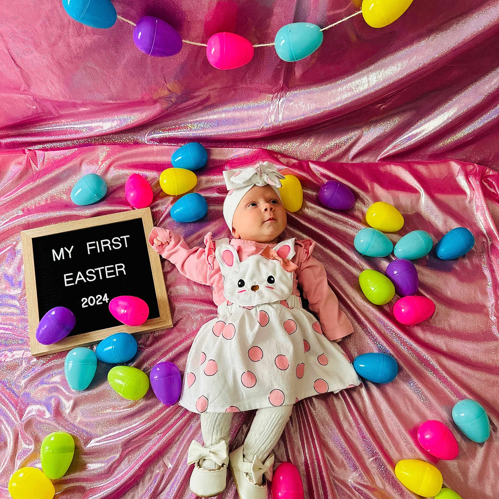 Eve is registered to the contest to win money with this photo: baby, balloon, clothing, egg, face, flower, food, hat, head, medication, people, person, petal, photography, pill, portrait, purple, sitting, sweets, toy