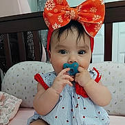 Paola is registered to the contest to win money with this photo: baby, infant, child, headband, red_bow, pacifier, crib, crib_rail, dress, ladybug_pattern, sitting, hands, dark_eyes, eyelashes, blanket, plush_toy, nursery, portrait, cute, clothing