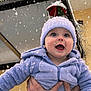 baby, child, snow, winter, outdoor, hat, blue_clothing, hands, smiling, face, snowflakes, joy, festive, decoration, cold_weather, cute, portrait, person, warm_clothing, hooded_jacket