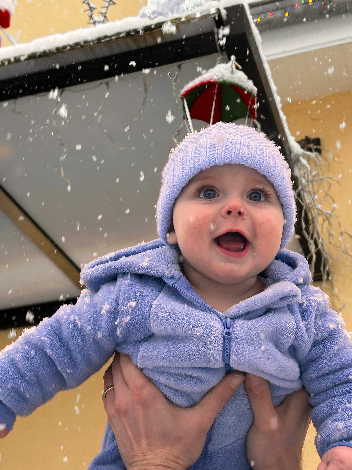 Lucian participe au concours pour gagner de l'argent avec cette photo : baby, child, snow, winter, outdoor, hat, blue_clothing, hands, smiling, face, snowflakes, joy, festive, decoration, cold_weather, cute, portrait, person, warm_clothing, hooded_jacket