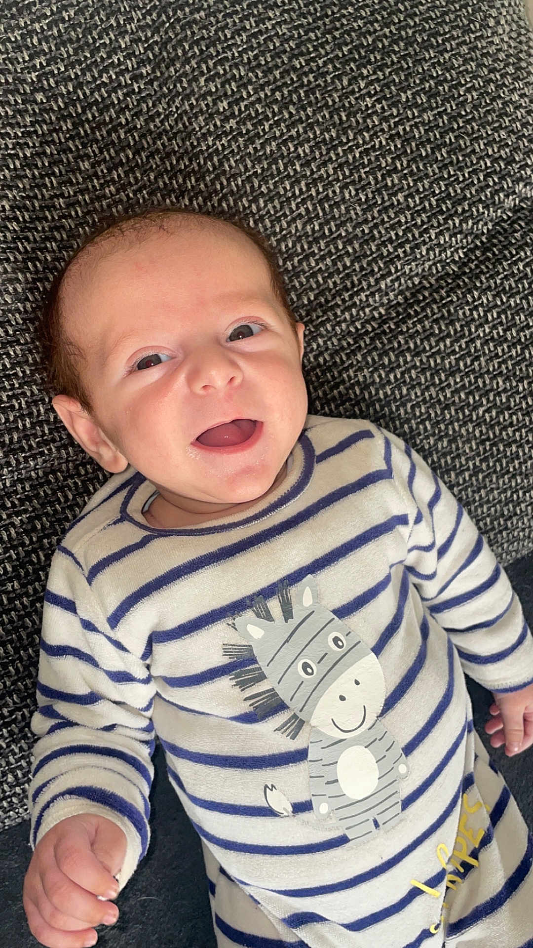 Maël participe au concours pour gagner de l'argent avec cette photo : baby, smiling, infant, striped_clothing, onesie, zebra_print, happy, face, person, cute, lying_down, hand, texture, blanket, indoor, closeup, newborn, child, expression, soft_fabric