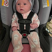 Hannah is registered to the contest to win money with this photo: baby, child, car_seat, onesie, pink, headband, bow, bunny_pattern, infant, straps, safety, seat, cute, indoor, clothing, person, young_child, face, expression, soft