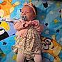 Hannah is registered to the contest to win money with this photo: baby, pacifier, pink_clothing, headband, blanket, cartoon_characters, patterned_dress, tights, infant, lying_down, cute, child, soft_lighting, indoors, colorful, playful, small_hands, face, expression, young_child