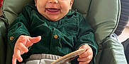 Kenzo a rejoint le concours — aidez-le/la à gagner de superbes lots ! baby, smiling, green_shirt, grey_pants, high_chair, indoor, happy, child, face, hand, book, card, laundry_basket, clothing, seat, person, portrait, furniture, expression, home