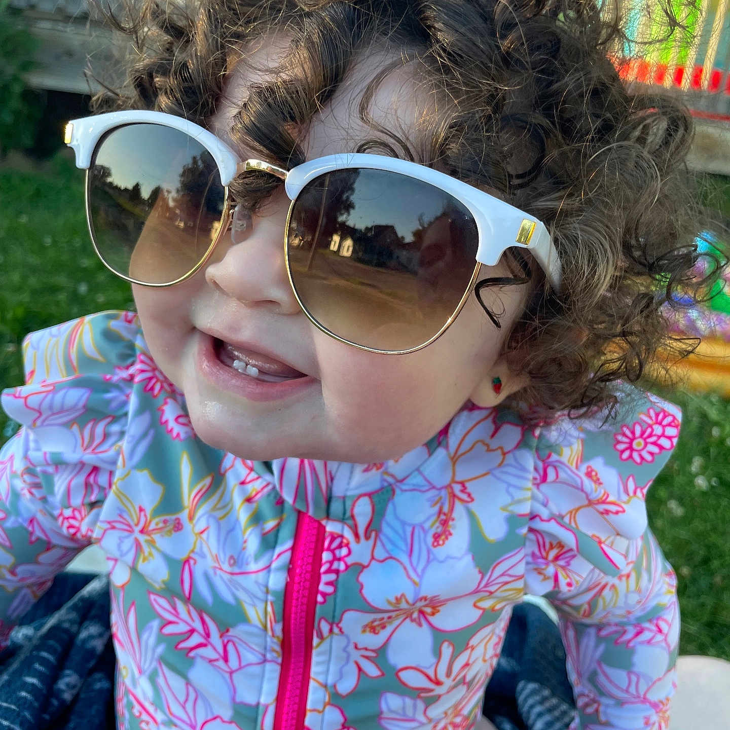 Sophia is registered to the contest to win money with this photo: accessories, baby, bodypart, clothing, coat, face, glasses, grass, happy, head, jacket, mouth, outdoors, person, photography, plant, portrait, smile, summer, sunglasses