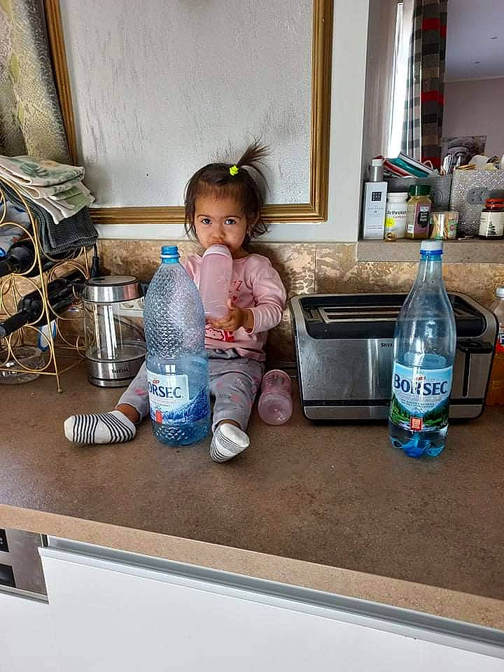 Rosalina participe au concours pour gagner de l'argent avec cette photo : beauty, bottle, child, drink, drinkware, floor, flooring, foot, fun, gas, glass_bottle, happy, person, plastic_bottle, play, room, sitting, standing, toddler, water_bottle