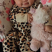 Xiomara joined the competition — help win amazing prizes! baby, child, comfort, cute, face, floral_pattern, hand, happy, indoor, infant, leopard_print, onesie, patterned_clothing, pillow, plush_toy, portrait, resting, smile, soft_toy, unicorn