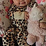 baby, child, comfort, cute, face, floral_pattern, hand, happy, indoor, infant, leopard_print, onesie, patterned_clothing, pillow, plush_toy, portrait, resting, smile, soft_toy, unicorn