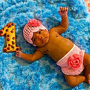 Essence joined the competition — help win amazing prizes! baby, infant, crochet, hat, diaper_cover, rose, blue_rug, cookie, number_one, chocolate_chips, lying_down, cute, celebration, milestone, soft_texture, hand_raised, barefoot, portrait, indoors, child