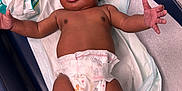 Essence joined the competition — help win amazing prizes! baby, infant, diaper, baby_wipes, medical_table, curly_hair, skin, arms, legs, expression, healthcare, clinic, cute, newborn, child, person, laying_down, indoors, mickey_mouse, waiting
