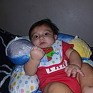 Amar joined the competition — help win amazing prizes! baby, bib, blanket, child, cushion, cute, expression, face, furniture, hand, indoor, infant, looking_at_camera, person, pillow, polka_dot, red_clothing, sitting, skin, young