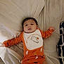 Amar is registered to the contest to win money with this photo: baby, bed, bib, blanket, child, cute, fabric, ghost, halloween, indoors, infant, lying_down, onesie, orange_clothing, person, pumpkin, relaxed, sleepwear, soft_lighting, young