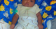 Kareem is registered to the contest to win money with this photo: baby, infant, child, portrait, lying_down, blanket, blue_blanket, pacifier, onesie, sleepwear, smiling, face, eyes, indoor, living_room, couch, furniture, colorful, animal_pattern, timestamp