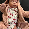 baby, infant, child, cute, face, clothing, jacket, onesie, pattern, cherry, pink, fuzzy, warm, lying_down, person, indoor, portrait, soft_texture, young, adorable