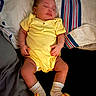 Nova Rios is registered to the contest to win money with this photo: baby, sleeping, yellow_onesie, socks, bed, blanket, pillow, infant, child, cute, peaceful, indoors, resting, person, toddler, soft_lighting, comfortable, clothing, lying_down, young_child