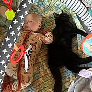 Murphy is registered to the contest to win money with this photo: baby, cat, sleeping, black_cat, baby_pajamas, blanket, playpen, toy, hanging_toy, patterned_clothing, indoor, resting, pet, infant, closeup, child, soft_texture, animal_print, peaceful, cozy