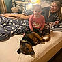 baby, dog, woman, bed, lamp, comforter, smile, happy, indoor, bedroom, furniture, pajamas, glasses, relaxing, pet, family, blanket, legs, light, home