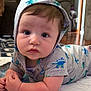 Matthew joined the competition — help win amazing prizes! baby, infant, child, hoodie, dinosaur_pattern, cute, indoors, floor, blanket, curious, face, arms, clothing, living_room, carpet, wooden_floor, person, portrait, expression, toddler