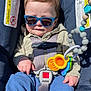 baby, child, sunglasses, car_seat, toy, blue_pants, jacket, sunlight, straps, seatbelt, infant, cute, hands, face, expression, indoors, safety, plastic_toys, closeup, portrait