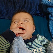 Lorrin is registered to the contest to win money with this photo: baby, infant, blanket, blue, striped_clothing, hand, mouth, face, sleepy, cozy, pillow, bed, soft_texture, cute, child, portrait, indoor, person, sleepwear, fuzzy