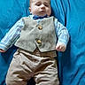 baby, child, infant, clothing, vest, bow_tie, shirt, pants, bed, blue_bed_sheet, person, portrait, indoor, cute, fashion, laying_down, young_child, face, serious_expression, casual