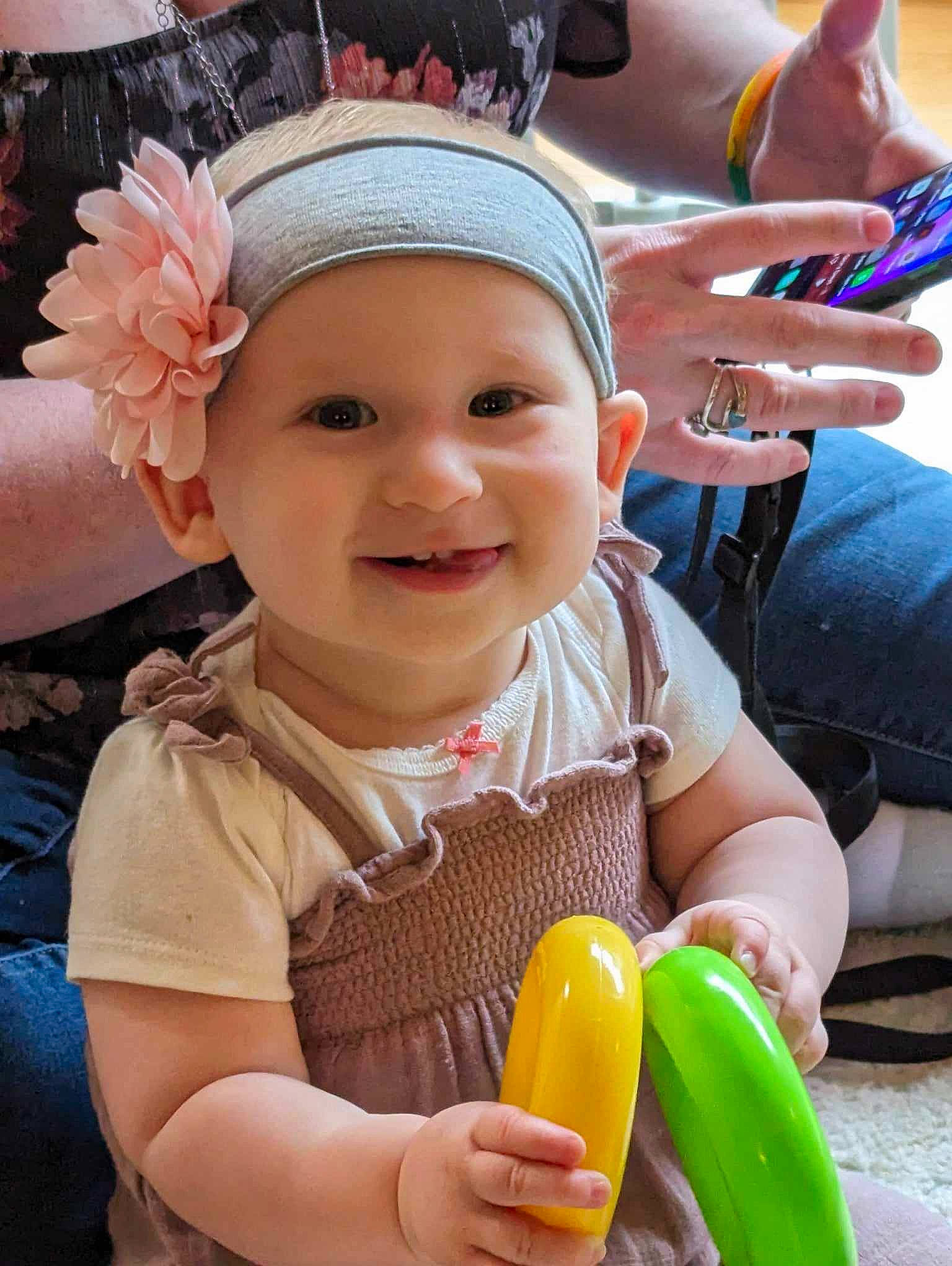 Aleena is registered to the contest to win money with this photo: baby, baby_toddler_clothing, cap, child, finger, flower, fun, gesture, happy, headwear, joy, leisure, people, person, petal, photograph, pink, plant, skin, smile