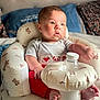 cushion, homedecor, face, head, person, photography, portrait, people, baby, couch, furniture, pillow, newborn, sitting, blanket, bodypart, finger, hand, ball, football