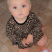 Araya is registered to the contest to win money with this photo: baby, child, toddler, sitting, floor, tile, leopard_print, dress, hair_bow, pink, face, eyes, hands, legs, sippy_cup, indoor, curious, expression, person, clothing