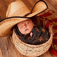 Oliver joined the competition — help win amazing prizes! baby, sleeping, basket, cowboy_hat, blanket, wooden_floor, infant, wrapped, face, peaceful, child, cozy, headwear, plush, portrait, resting, indoor, newborn, star_pattern, woven