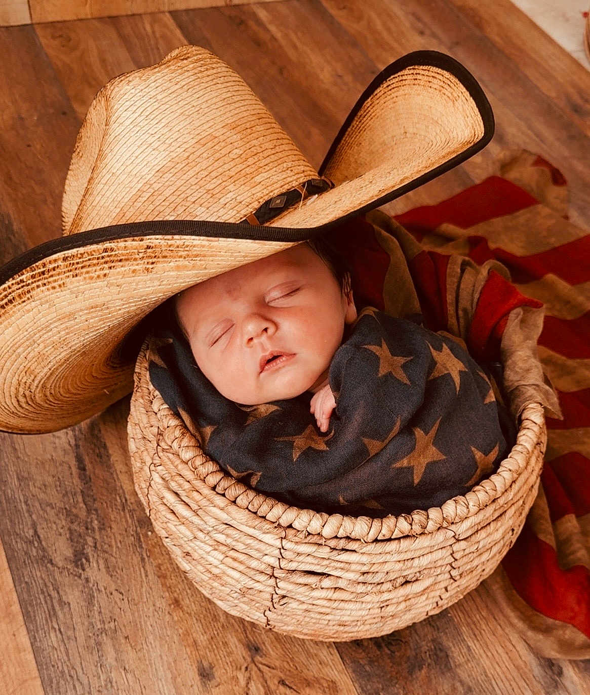 Oliver joined the competition — help win amazing prizes! baby, sleeping, basket, cowboy_hat, blanket, wooden_floor, infant, wrapped, face, peaceful, child, cozy, headwear, plush, portrait, resting, indoor, newborn, star_pattern, woven