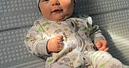Mav joined the competition — help win amazing prizes! baby, infant, child, portrait, lying_down, onesie, knit_cap, smiling, face, eyes, hands, feet, mattress, bed, textile, indoor, cozy, patterned_clothing, photography, safe