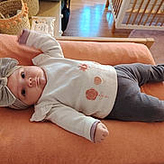 Zoéline a rejoint le concours — aidez-le/la à gagner de superbes lots ! baby, baby_clothes, baby_wipes, child, clothing, cozy_room, crib, cute, floral_embroidery, headband, headwear, indoors, infant, lying_down, orange_blanket, person, soft_lighting, toddler, white_sweater, wooden_floor