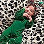 baby, infant, green_outfit, ruffles, bow, headwear, blanket, leopard_print, pattern, white_socks, cute, portrait, indoor, soft_texture, holiday_theme, christmas, child, person, resting, young