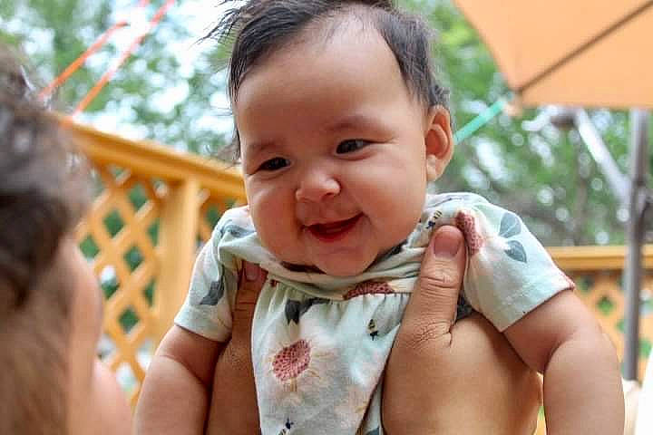 Kailani joined the competition — help win amazing prizes! baby, baby_toddler_clothing, cheek, child, finger, fun, gesture, grass, happy, iris, leisure, nose, people_in_nature, person, plant, sitting, skin, smile, thumb, toddler