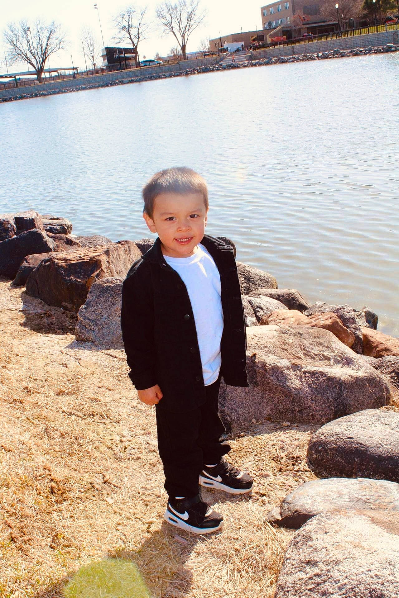 Kaisen is registered to the contest to win money with this photo: body_of_water, building, eye, formal_wear, fun, happy, lake, landscape, leisure, people_in_nature, person, sitting, sky, soil, standing, toddler, travel, tree, trousers, water