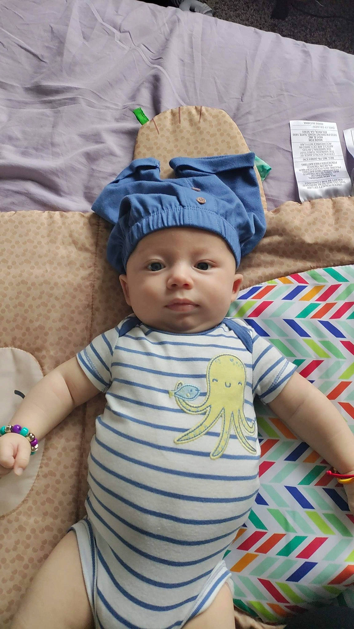 Marcus is registered to the contest to win money with this photo: baby, baby_toddler_clothing, cap, chair, cheek, child, comfort, couch, eye, facial_expression, fashion_accessory, happy, hat, headwear, mammal, pattern, person, sitting, skin, sleeve