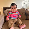 Maverick is registered to the contest to win money with this photo: baby, child, infant, sitting, couch, portrait, indoors, home, striped_shirt, colorful_clothing, brown_pants, bare_feet, smiling, wide_eyes, dark_hair, face, hands, legs, furniture, photography